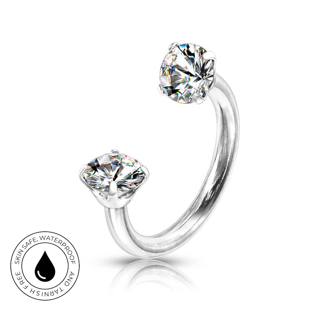 A silver-toned curved ring with two clear gemstones in a prong setting, shown on a white background with a small circular skin-safe waterproof badge in the lower left.