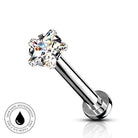 A silver-toned labret piercing barbell with a clear, multi-prong gemstone setting on a white background, featuring a circular 'SkinSafe Waterproof' badge in the lower-left corner.