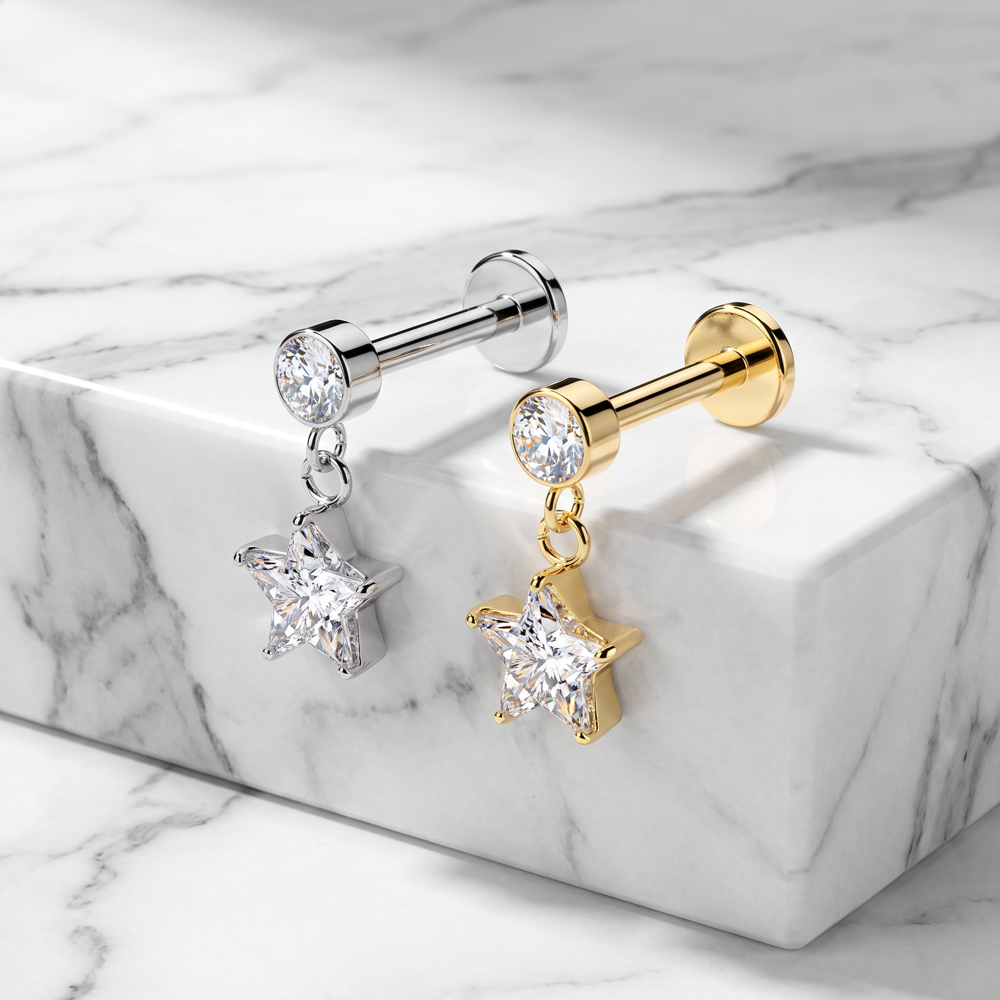 Two star-shaped dangle earrings displayed on a white marble block. One earring is silver-toned with a clear faceted gemstone, and the other is gold-toned with a matching clear gemstone.