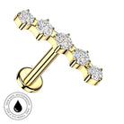 A gold T-bar stud piercing jewelry piece featuring five round-cut clear gemstones set along the top bar, shown on a plain white background with a circular 'Skin Safe Waterproof' badge in the lower-left corner.