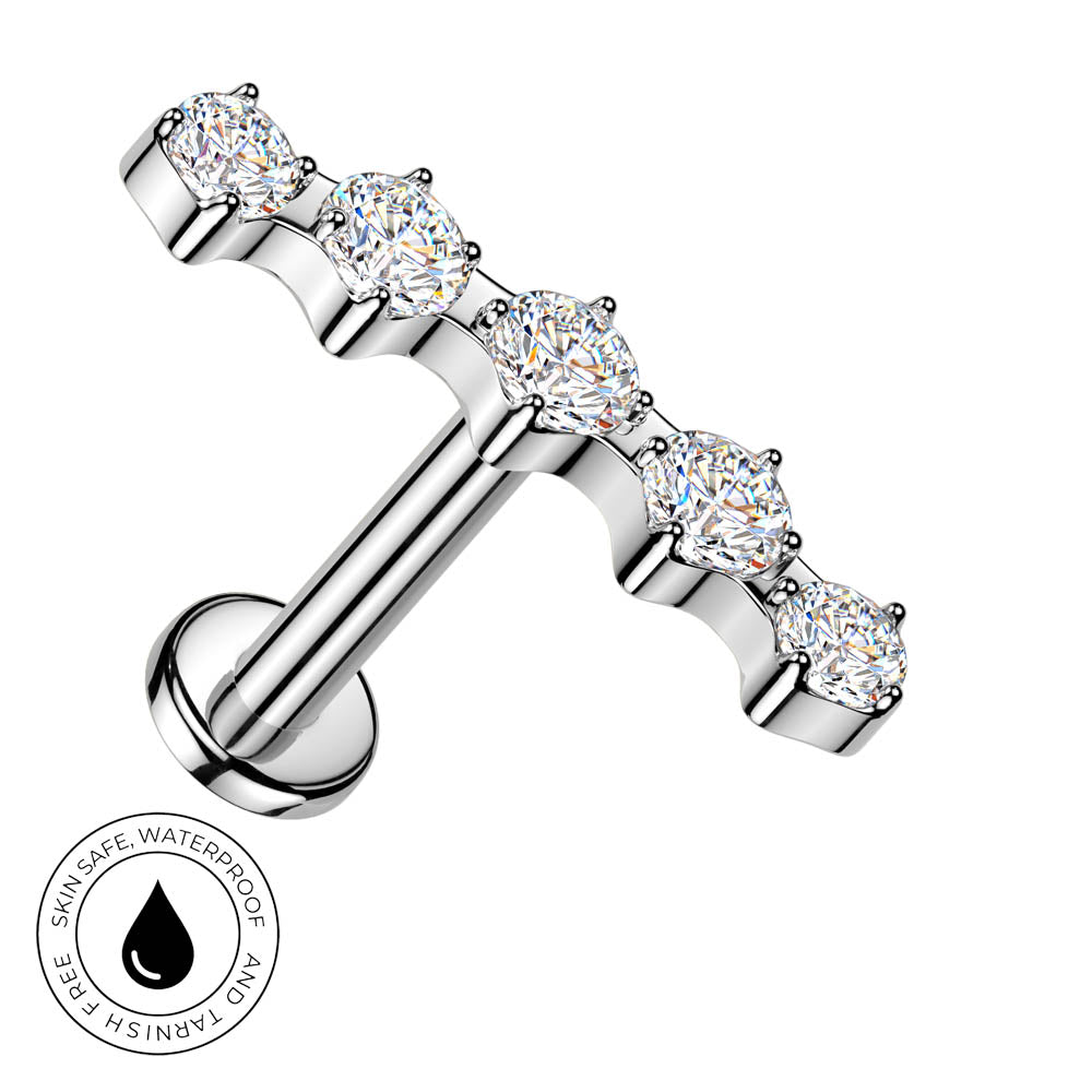 A silver-toned T-bar labret piercing stud with five round-cut clear gemstones, shown on a plain white background with a circular 'skin-safe waterproof' badge in the lower-left corner.
