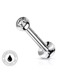 A silver-toned curved barbell piercing stud with a clear faceted gemstone on one end and a round polished back, shown on a white background with a small circular 'skin-safe waterproof' badge in the lower left.