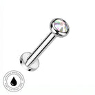 A silver-toned labret piercing barbell with a faceted iridescent clear gemstone ball end, shown on a plain white background with a circular 'Skin Safe Waterproof' badge in the lower-left corner.