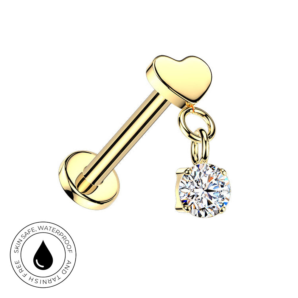Gold barbell lobe piercing stud with a heart-shaped top and a dangling round clear gemstone charm, shown on a white background with a small skin-safe waterproof badge in the lower-left corner.
