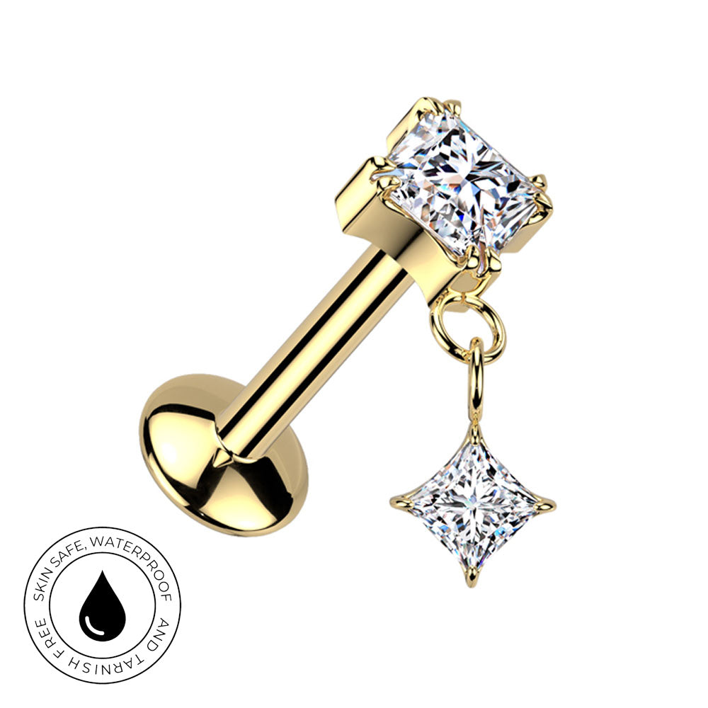 Gold-plated labret piercing stud with a princess-cut clear gemstone top and a dangling star-shaped clear gemstone charm, shown on a white background with a circular skin-safe waterproof badge in the lower-left corner.