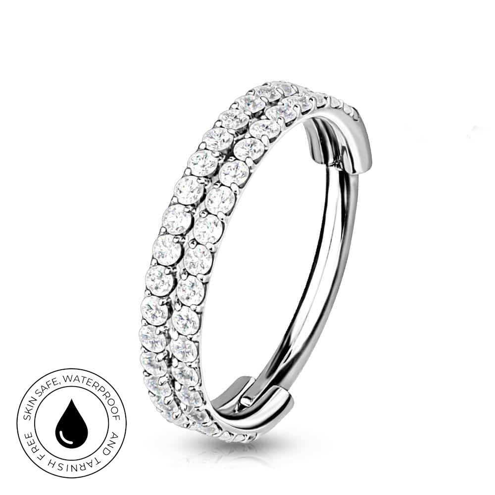 A silver-toned curved huggie hoop ring adorned with two rows of clear round-cut stones, shown on a white background with a circular 'Skin Safe Waterproof' badge in the lower-left corner.