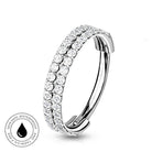 A silver-toned curved huggie hoop ring adorned with two rows of clear round-cut stones, shown on a white background with a circular 'Skin Safe Waterproof' badge in the lower-left corner.