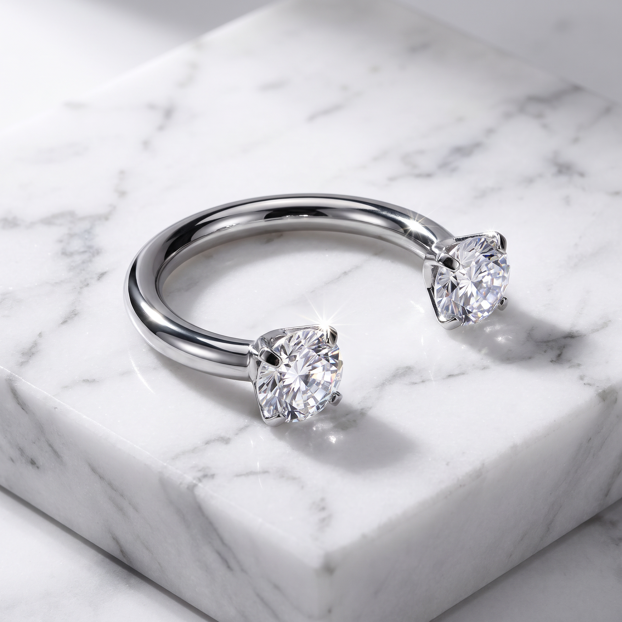 A silver circular barbells with two square-cut clear gemstones, displayed on a white marble block.