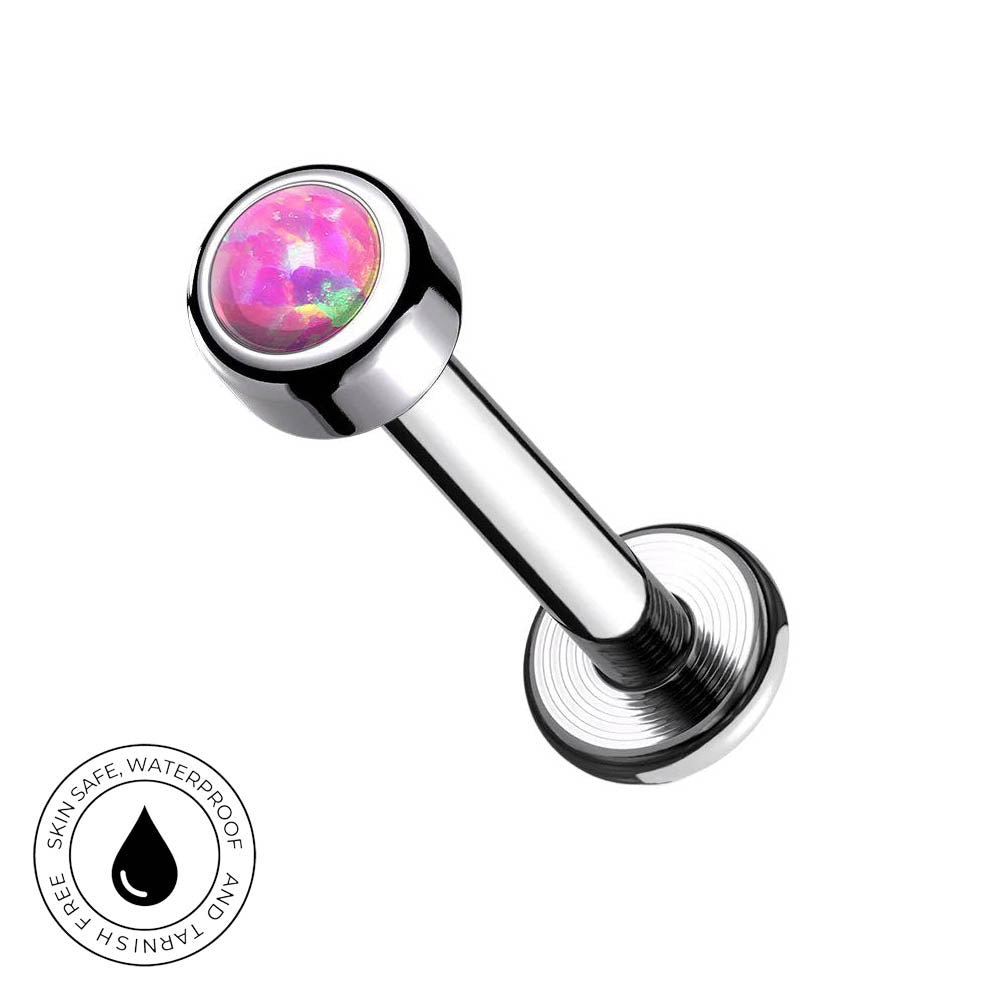 A stainless steel labret piercing barbell with a round pink opal inlay on the end, shown on a white background with a circular 'Skin Safe Waterproof' badge in the bottom-left corner.