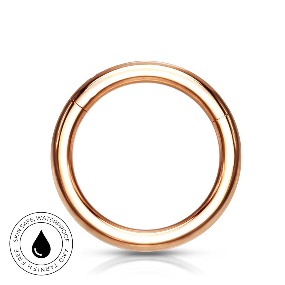 A rose gold metal ring piercing closure on a white background with a small circular badge in the bottom-left corner that reads 'SKINSAFE WATERPROOF AND TARNISH FREE' with a water droplet icon.