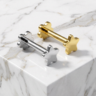 Two metallic star-and-bolt decorative hardware pieces, one polished silver and one polished gold, displayed on a white marble surface.