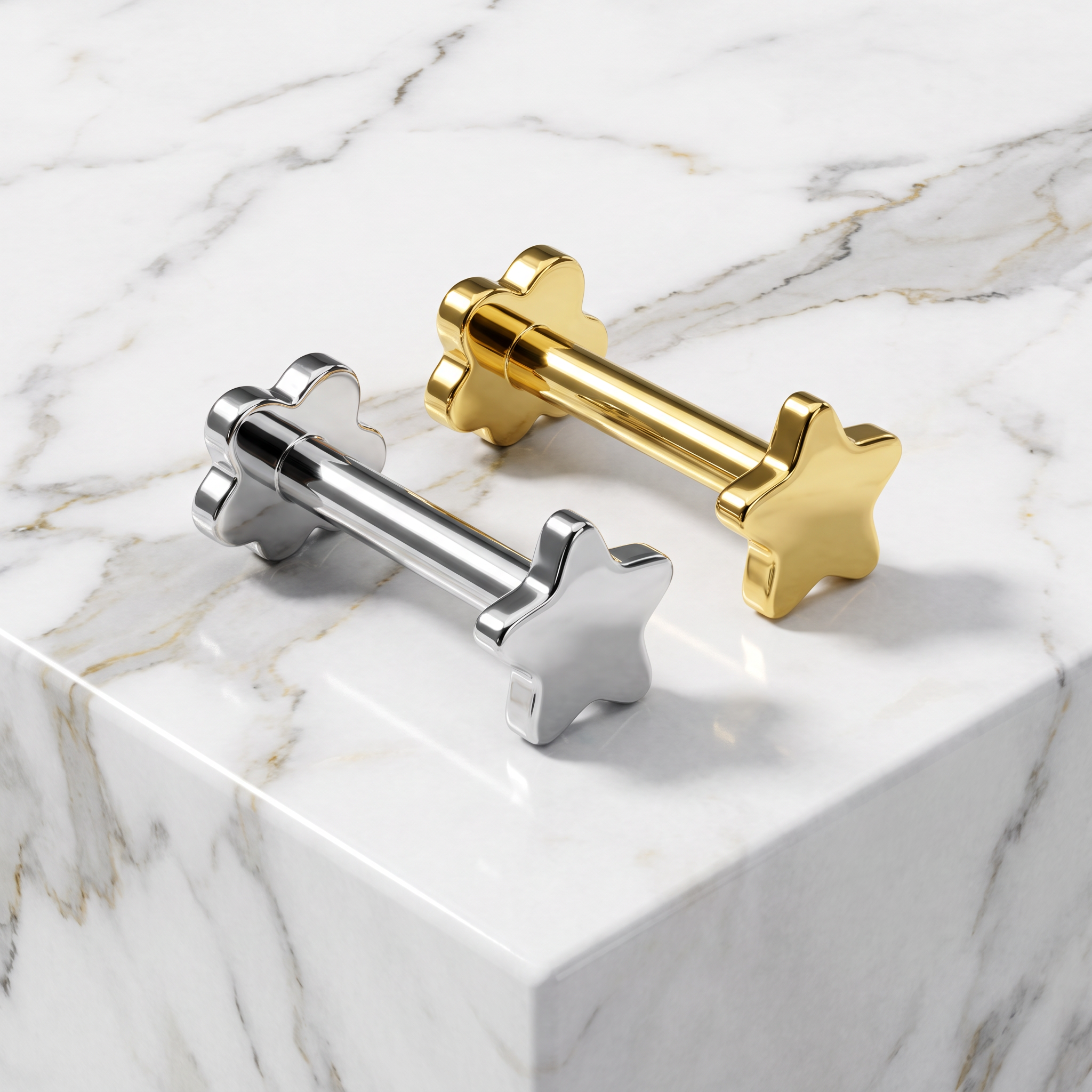 Two metallic star-and-bolt decorative hardware pieces, one polished silver and one polished gold, displayed on a white marble surface.