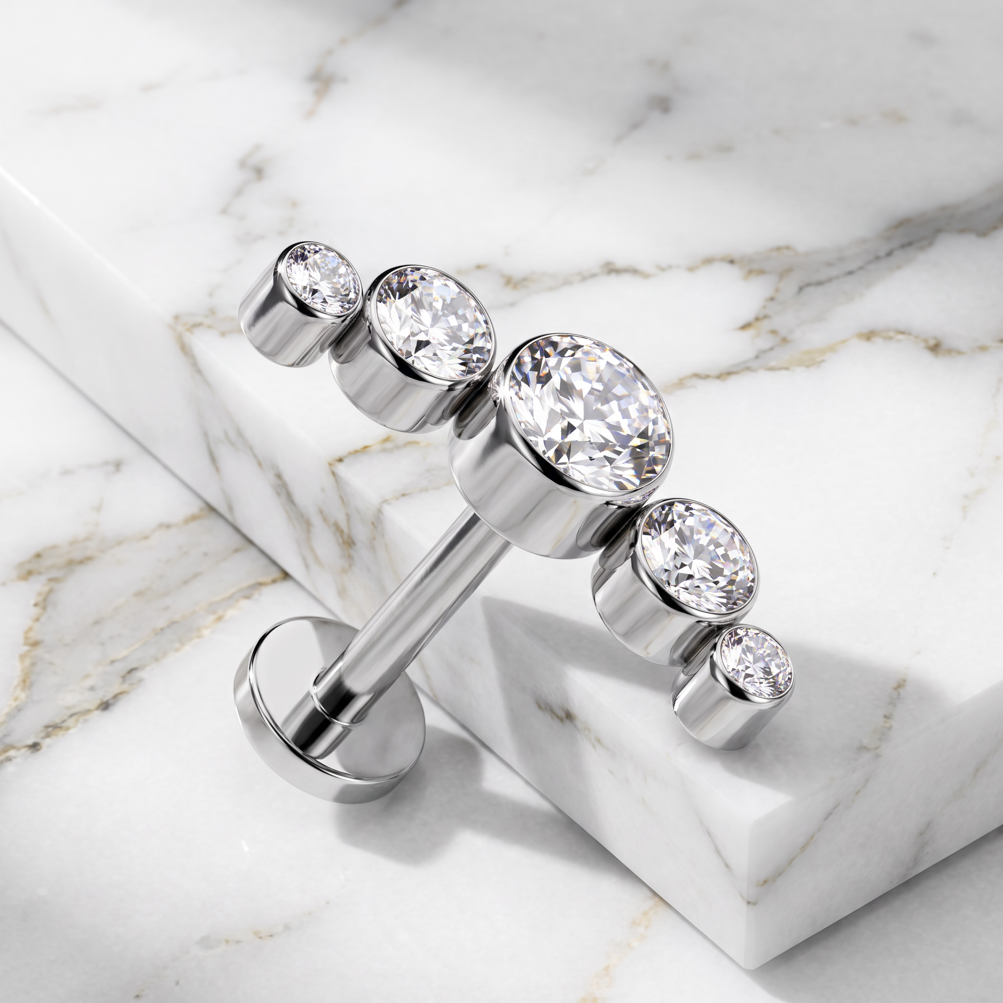 A silver-toned barbell-style body jewelry piece with five clear faceted gemstones of varying sizes, displayed on a white marble slab over a marble surface.