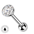 A silver-toned labret piercing barbell with a large round clear faceted gemstone on one end and a polished ball on the other, shown on a white background with a small circular skin-safe waterproof badge in the lower left.