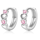 A pair of silver huggie hoop earrings decorated with three stacked heart charms, each accented with a round pink gemstone, shown on a clean white background with a soft reflection.