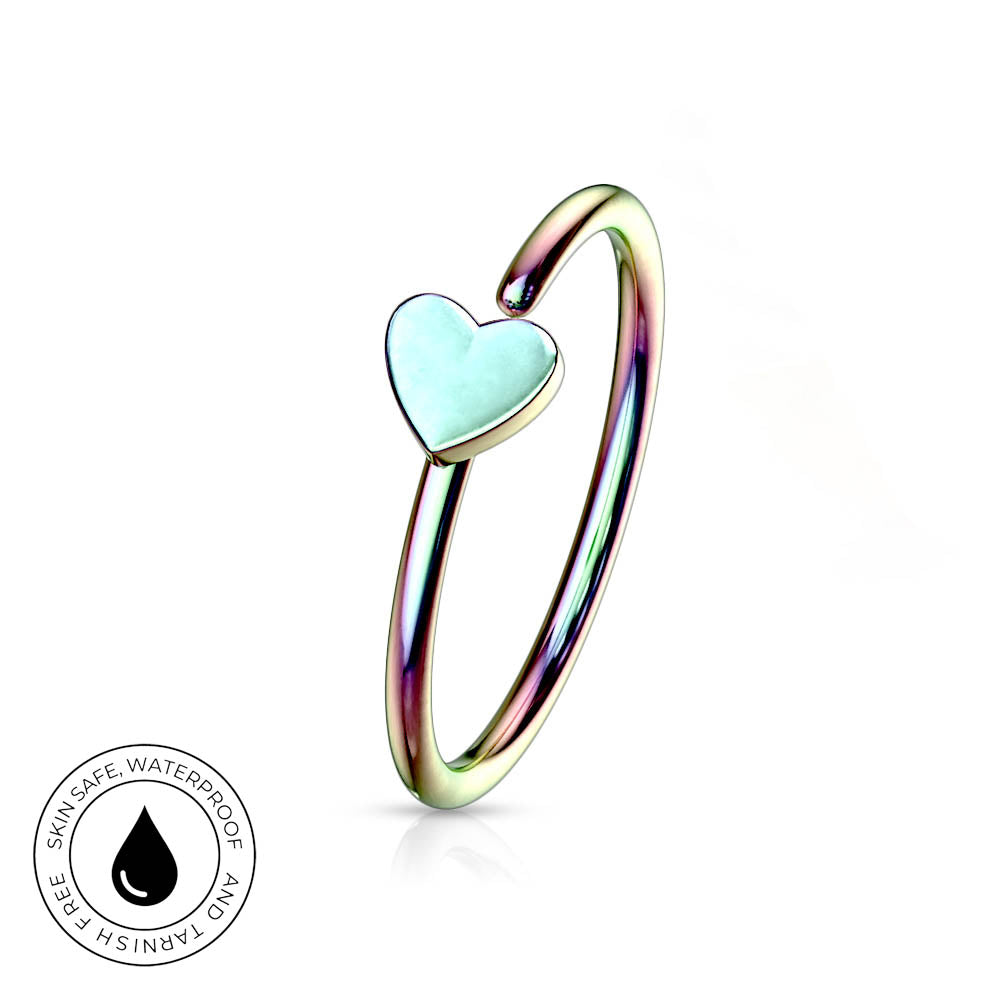 An iridescent gold-plated ring with a small, light blue-green heart-shaped inlay, shown on a white background with a circular 'Skin Safe Waterproof' certification badge in the bottom-left corner.
