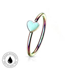 An iridescent gold-plated ring with a small, light blue-green heart-shaped inlay, shown on a white background with a circular 'Skin Safe Waterproof' certification badge in the bottom-left corner.