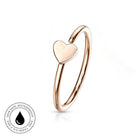A rose gold open wrap ring with a small flat heart charm, shown on a clean white background with a circular 'Skin Safe Waterproof' badge in the bottom-left corner.