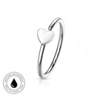 A polished silver-toned ring with a small heart-shaped charm, shown on a clean white background with a circular 'Skin Safe Waterproof' badge in the lower-left corner.