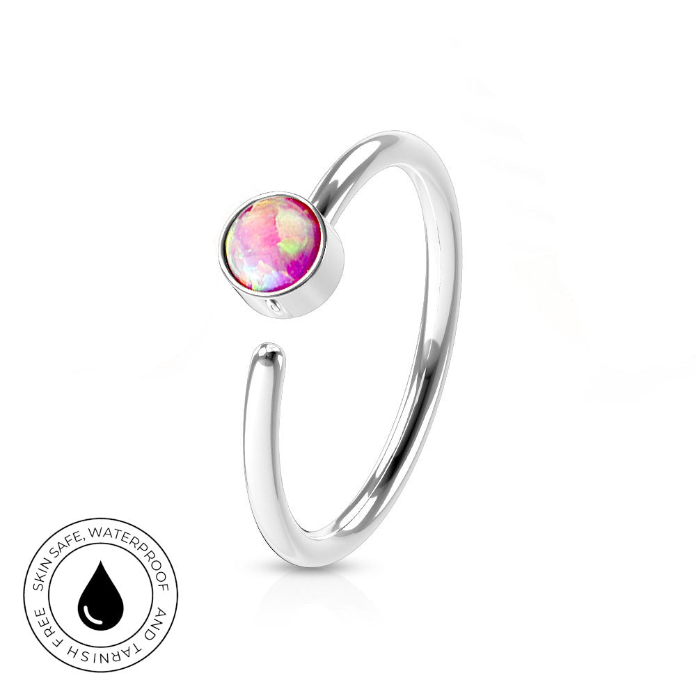 A silver-toned open bangle ring with a round bezel-set iridescent pink and purple stone, shown on a white background with a small circular 'skin-safe waterproof' badge in the lower left.