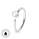 A silver-toned open ring with a round iridescent opal-like stone, shown on a clean white background. A small circular badge in the lower left reads 'SKINSAFE WATERPROOF AND TARNISH FREE' with a black droplet icon.