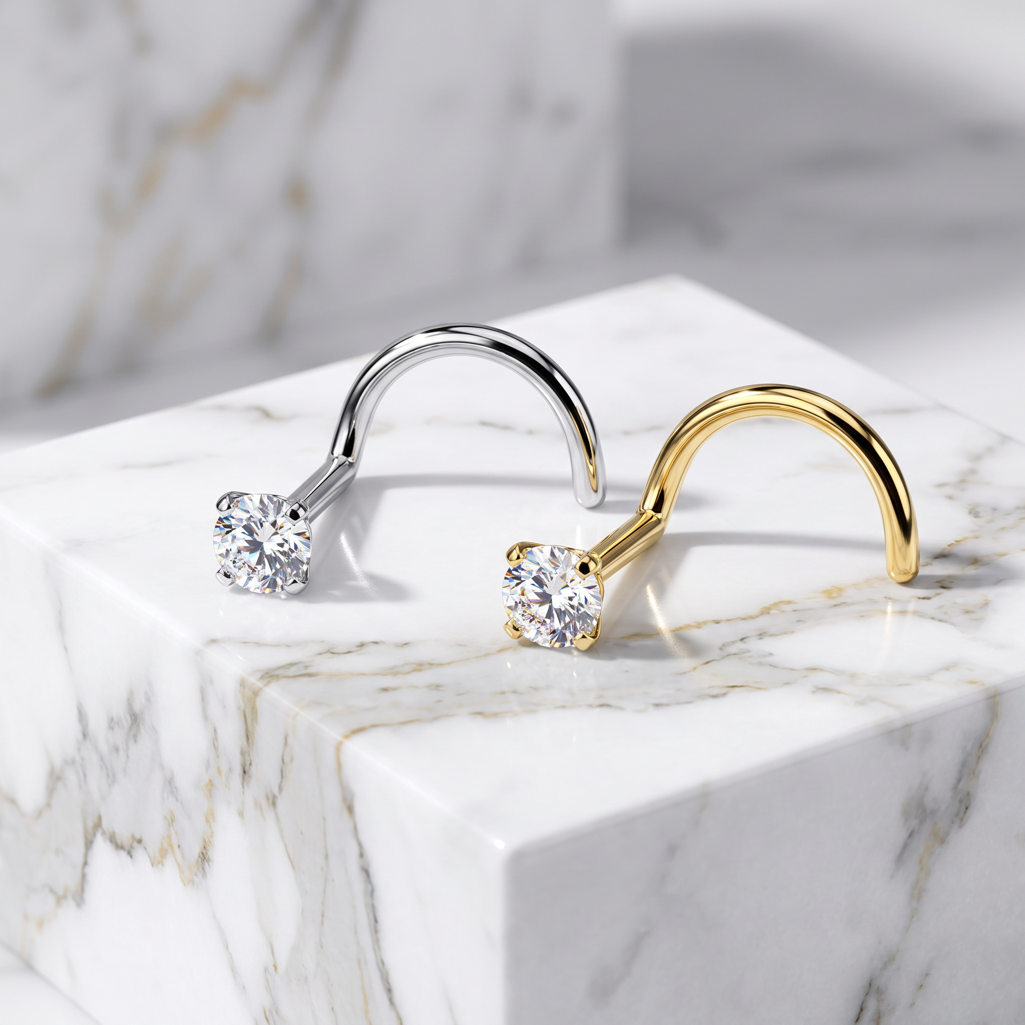 Two curved hoop-style earrings displayed on a white marble block. One earring is silver-toned with a clear round gemstone, and the other is gold-toned with a matching clear round gemstone.