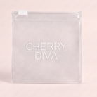 A clear plastic zippered pouch with a white zipper tab and the brand name 'CHERRY DIVA' printed in white on the front, set against a solid pale pink background.