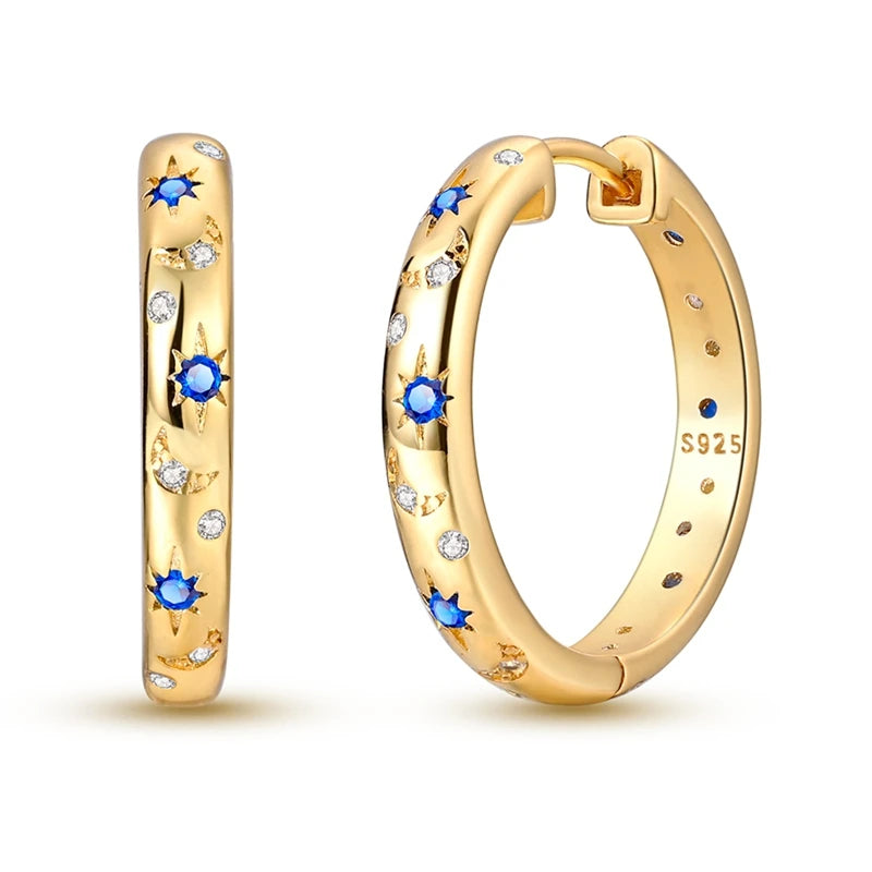 Gold hoop earrings with blue gemstones on a white background