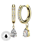 Gold huggie hoop earrings with clear pavé stones and a teardrop-shaped clear gemstone dangle, shown on a white background with a circular skin-safe waterproof badge.