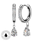 Silver huggie hoop earrings with clear pavé stones and teardrop-shaped clear gemstone drops, shown on a white background with a circular skin-safe waterproof badge.