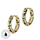 A pair of gold hoop earrings with a textured, faceted bamboo-like pattern, shown on a plain white background with a circular 'Skin Safe Waterproof' badge in the bottom-left corner.