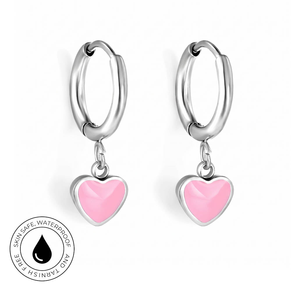 A pair of silver hoop earrings with dangling pink heart charms, shown on a clean white background with a circular 'Skin Safe Waterproof' certification badge in the bottom-left corner.