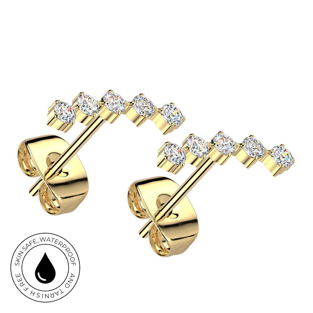 A pair of yellow gold post earrings with a curved row of round clear gemstones, shown on a white background with a circular 'Skin Safe Waterproof' badge in the lower left corner.