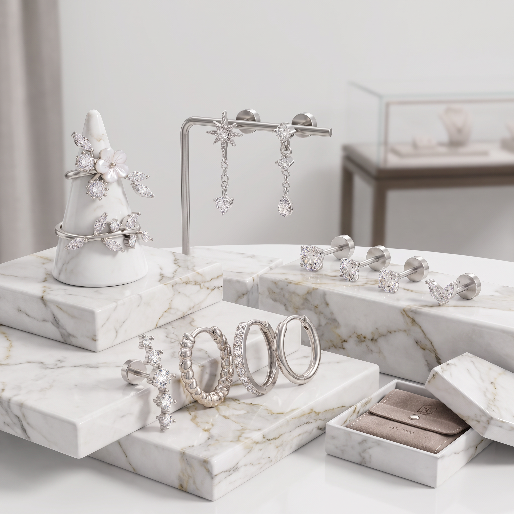 Silver-toned crystal jewelry displayed on white marble stands and trays, including hoop earrings, dangling earrings, stud earrings, and floral ring accents, with a small open jewelry box in the foreground.