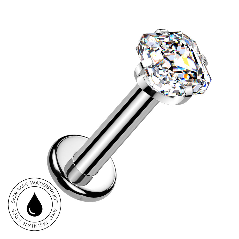 A silver-toned labret piercing barbell with a large, clear, faceted gemstone on the end. The image is set against a plain white background with a circular graphic overlay in the bottom-left corner that reads 'SKIN SAFE WATERPROOF' with a water droplet icon.