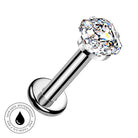 A silver-toned labret piercing barbell with a large, clear, faceted gemstone on the end. The image is set against a plain white background with a circular graphic overlay in the bottom-left corner that reads 'SKIN SAFE WATERPROOF' with a water droplet icon.