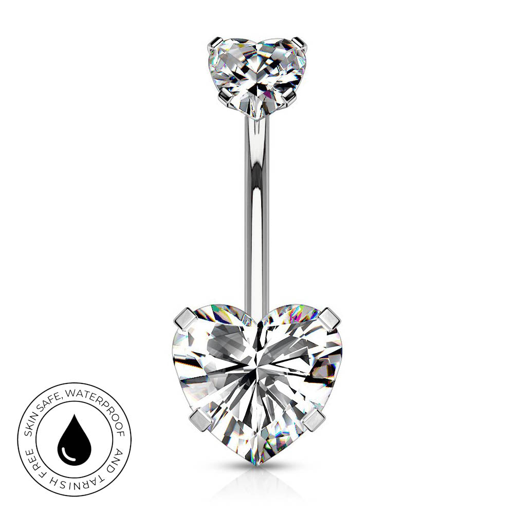 A silver-toned belly button ring with a heart-shaped clear gemstone at the bottom and a smaller heart-shaped gemstone at the top, shown on a white background with a circular skin-safe waterproof badge in the lower left.