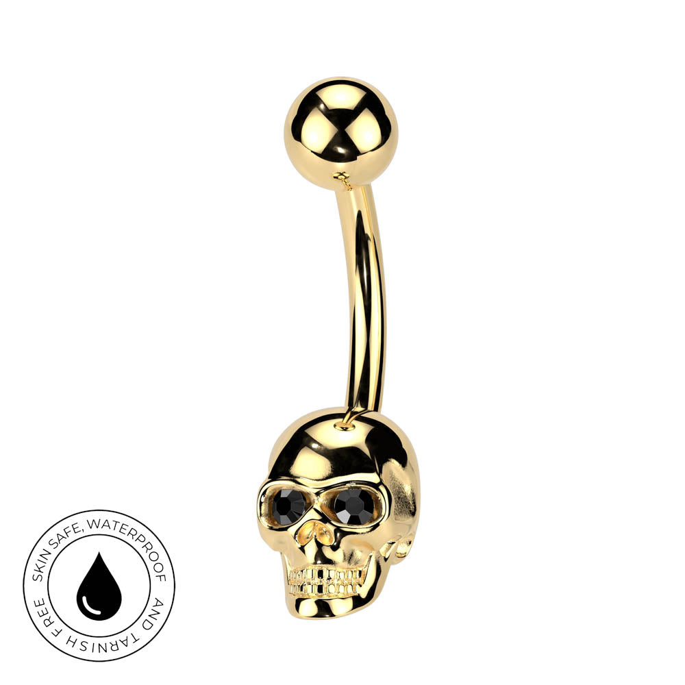 Gold-plated skull barbell piercing with skull eye details and a ball end, shown on a white background with a circular 'Skin Safe Waterproof' badge in the bottom-left corner.