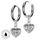 A pair of silver hoop earrings with dangling heart-shaped clear gemstone charms, shown on a white background with a circular skin-safe waterproof badge in the lower left corner.