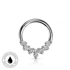 A silver-toned circular ring piercing with a decorative lower section featuring marquise-shaped clear stones, shown on a white background with a small circular 'skin-safe waterproof' badge in the lower left.