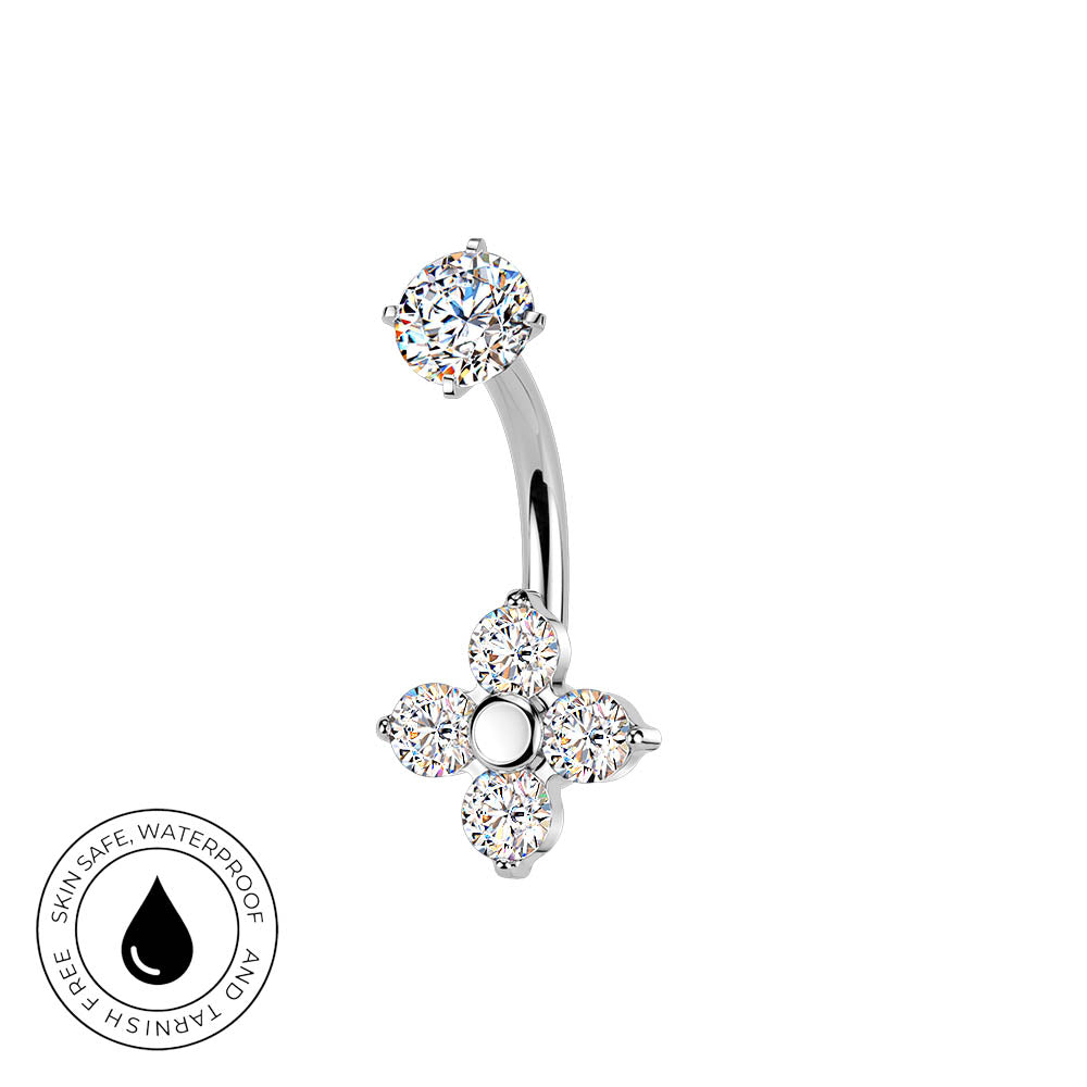 A curved barbell belly button ring with a flower-shaped dangling charm, both set with clear round gemstones in a silver-toned metal. A circular badge in the bottom-left corner reads 'SKIN SAFE WATERPROOF' with a black droplet symbol.
