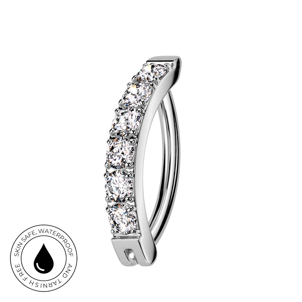 A silver-toned curved ring with a row of clear pavé-set stones, shown on a plain white background. A circular 'Skin Safe Waterproof' badge is visible in the bottom-left corner.