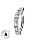 A silver-toned curved ring with a row of clear pavé-set stones, shown on a plain white background. A circular 'Skin Safe Waterproof' badge is visible in the bottom-left corner.